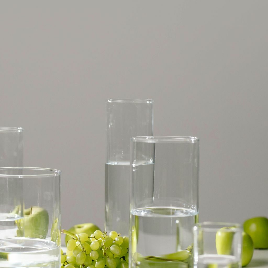 Un vaso de agua sobre una mesa junto a un racimo de uvas, favoreciendo la salud digestiva.