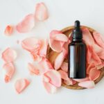 The Ultimate Guide to Banishing Oil with Aloe Vera for Your Hair Top view of empty brown bottle for skin care product placed on wooden plate with fresh pink rose petals on white background isolated