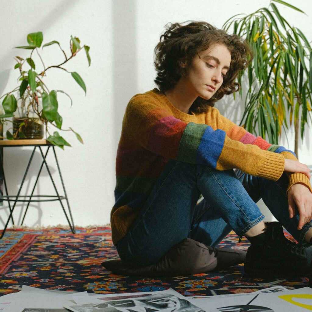 Lady sitting near paintings on floor in studio