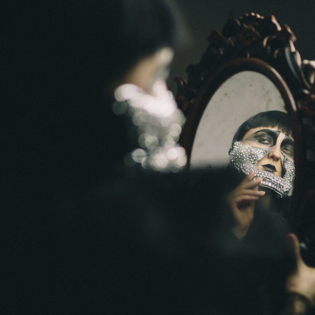 A woman with a face mask is looking in a mirror