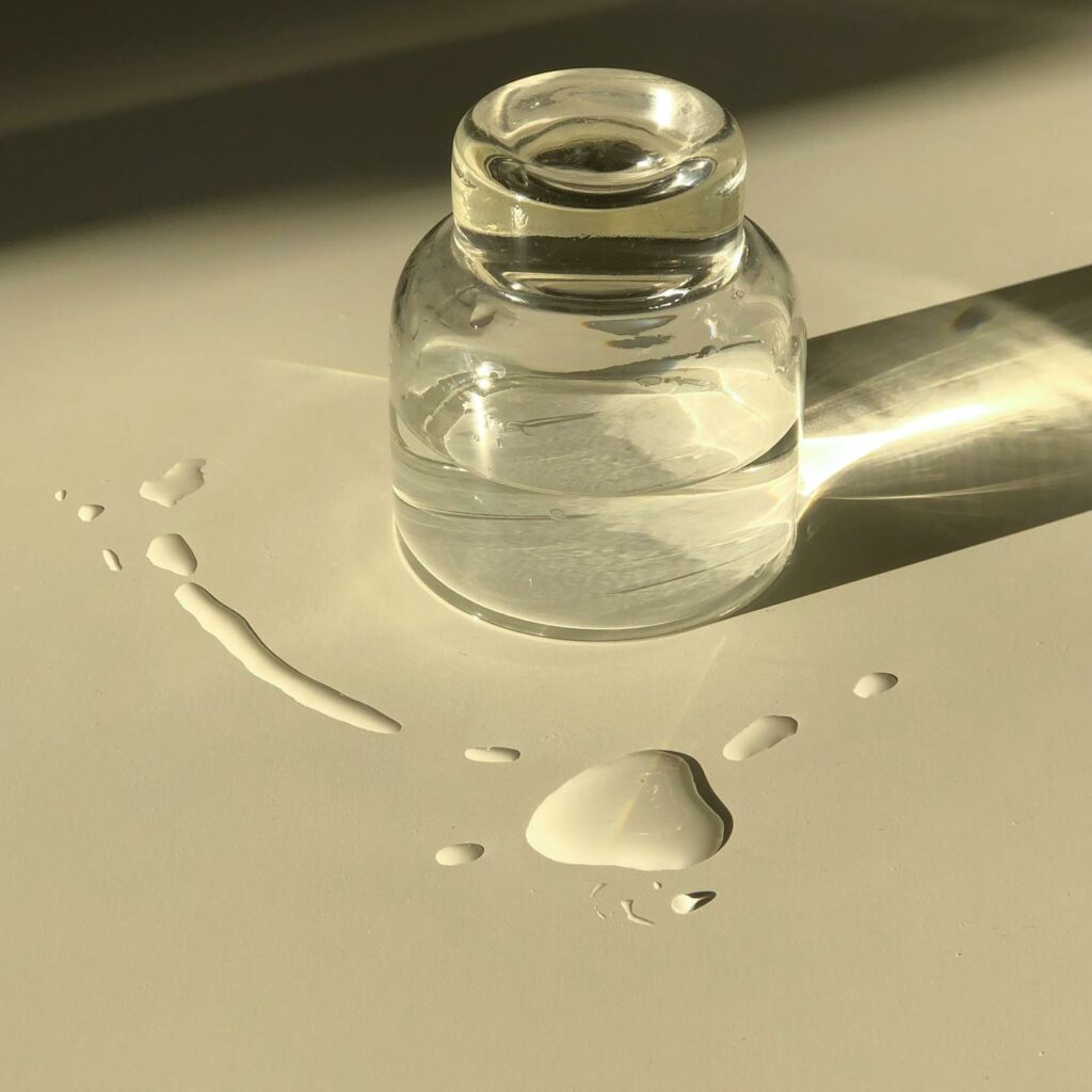 Glass jar with transparent liquid placed on white table