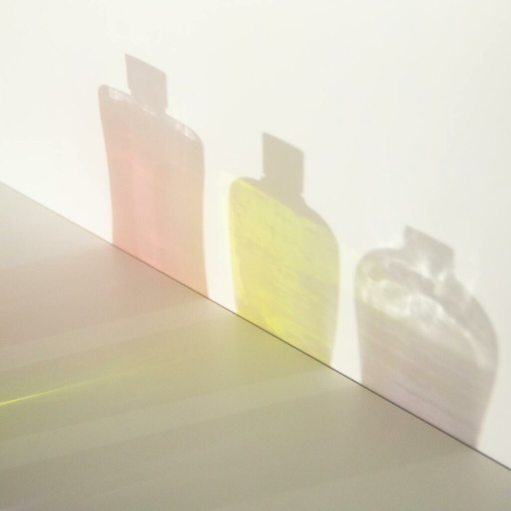 From above of different bottle shadows with bright liquids and caps in row on smooth surface