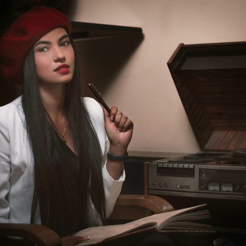 A woman in a beret sitting at a table with a record player