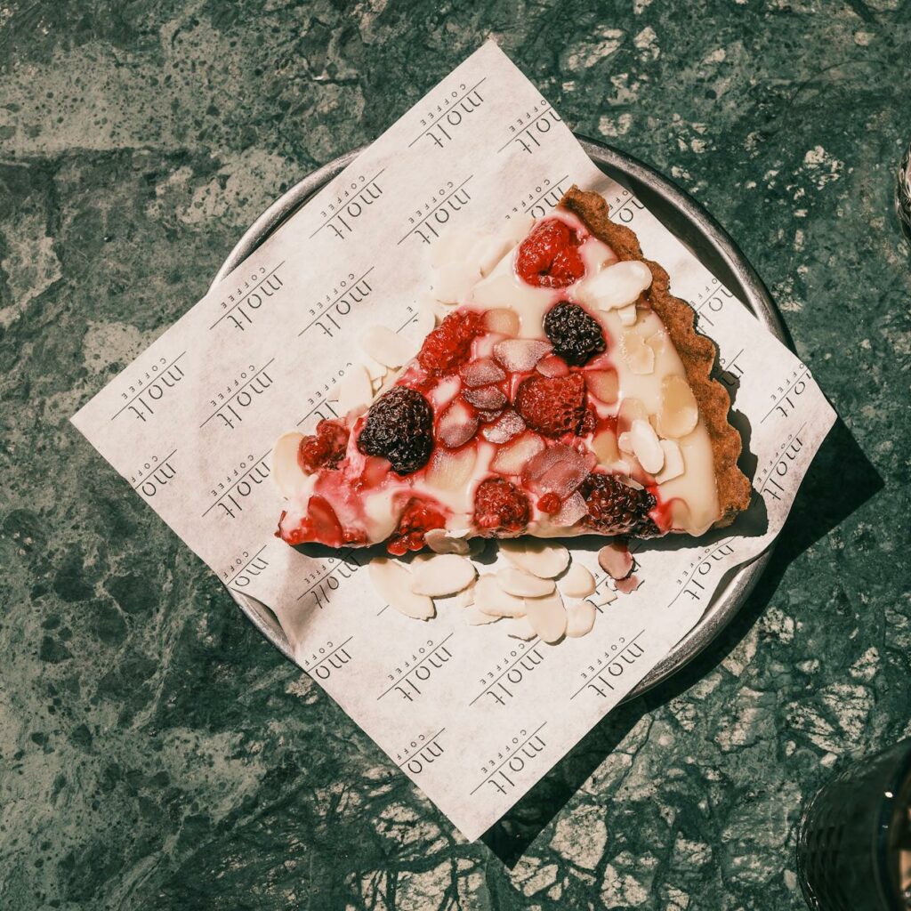 A slice of pizza on a plate next to a drink